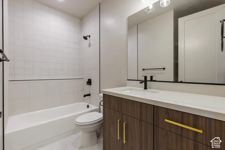 Built-in bathtub with subway tile surround, wood-finish vanity with gold-tone hardware, white countertop, and matte black fixtures