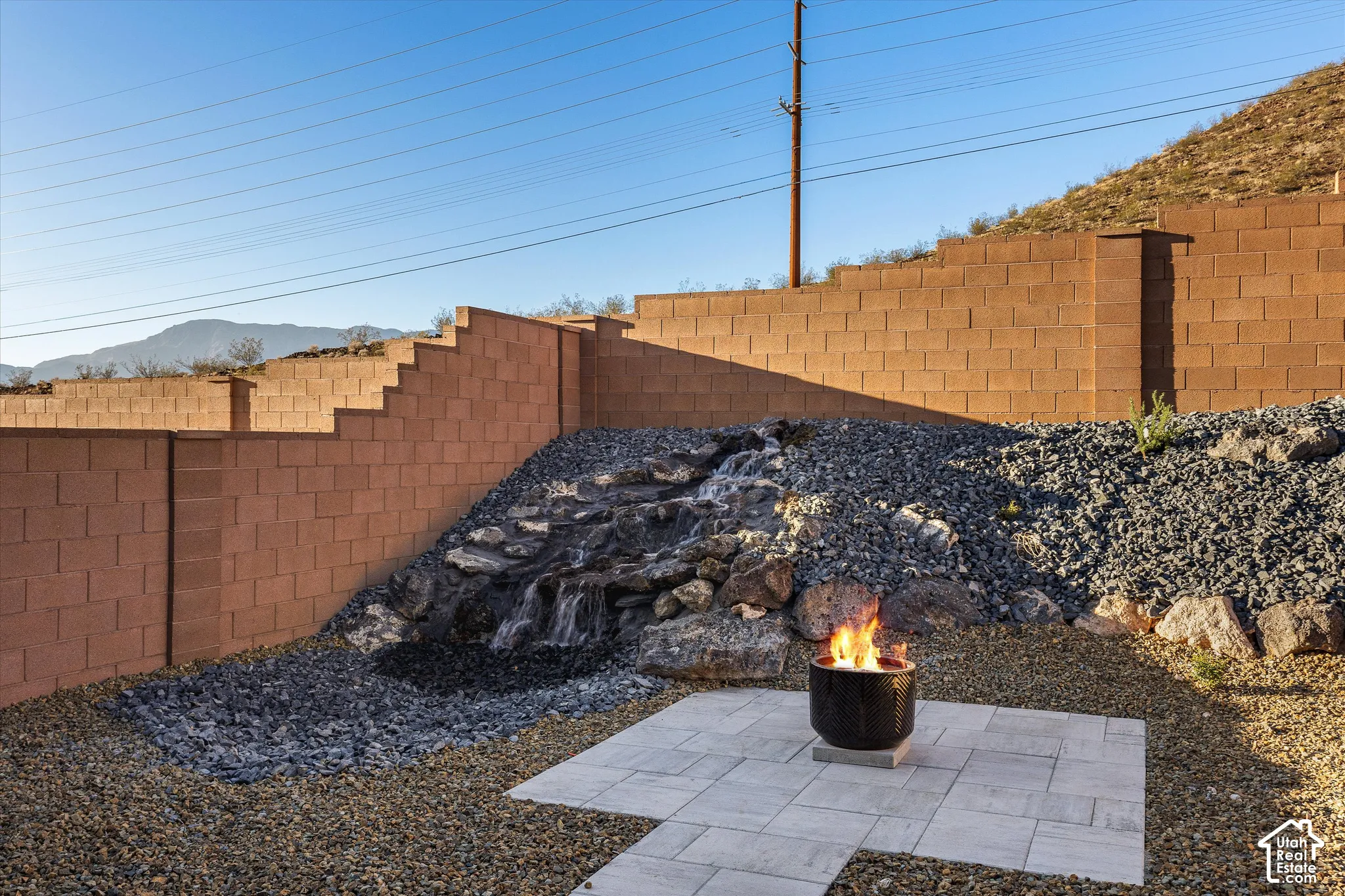 Backyard featuring a built-in waterfall, stone retaining wall, paver patio, and decorative gravel landscaping