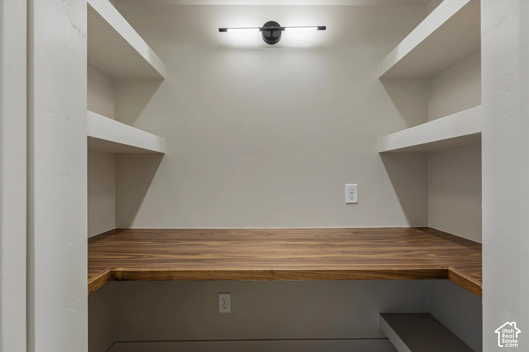 Built-in shelving with wood-finish countertop and overhead linear light fixture
