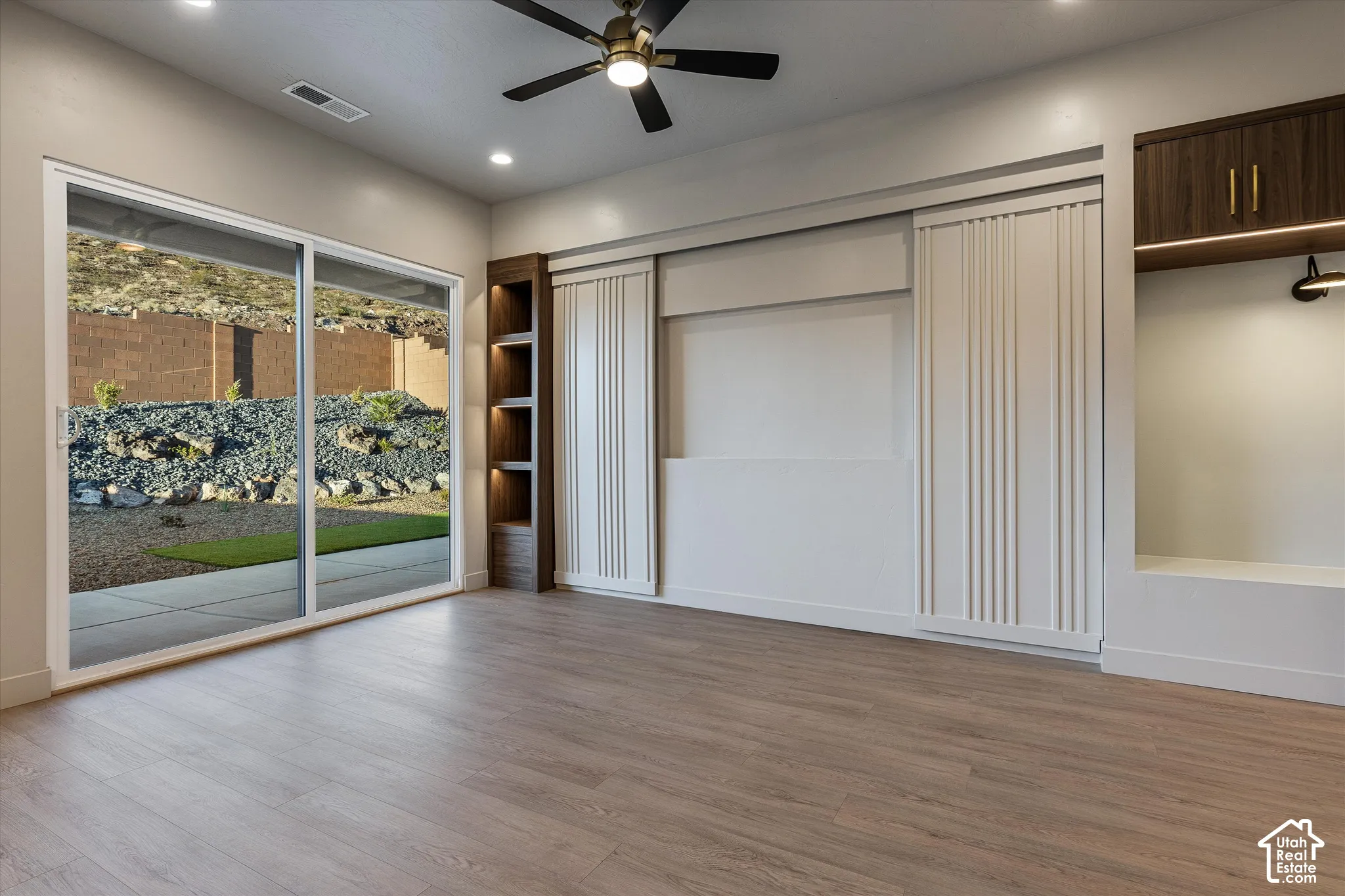 Wood-finish flooring, sliding glass door, built-in shelving, built-in cabinetry, and ceiling fan