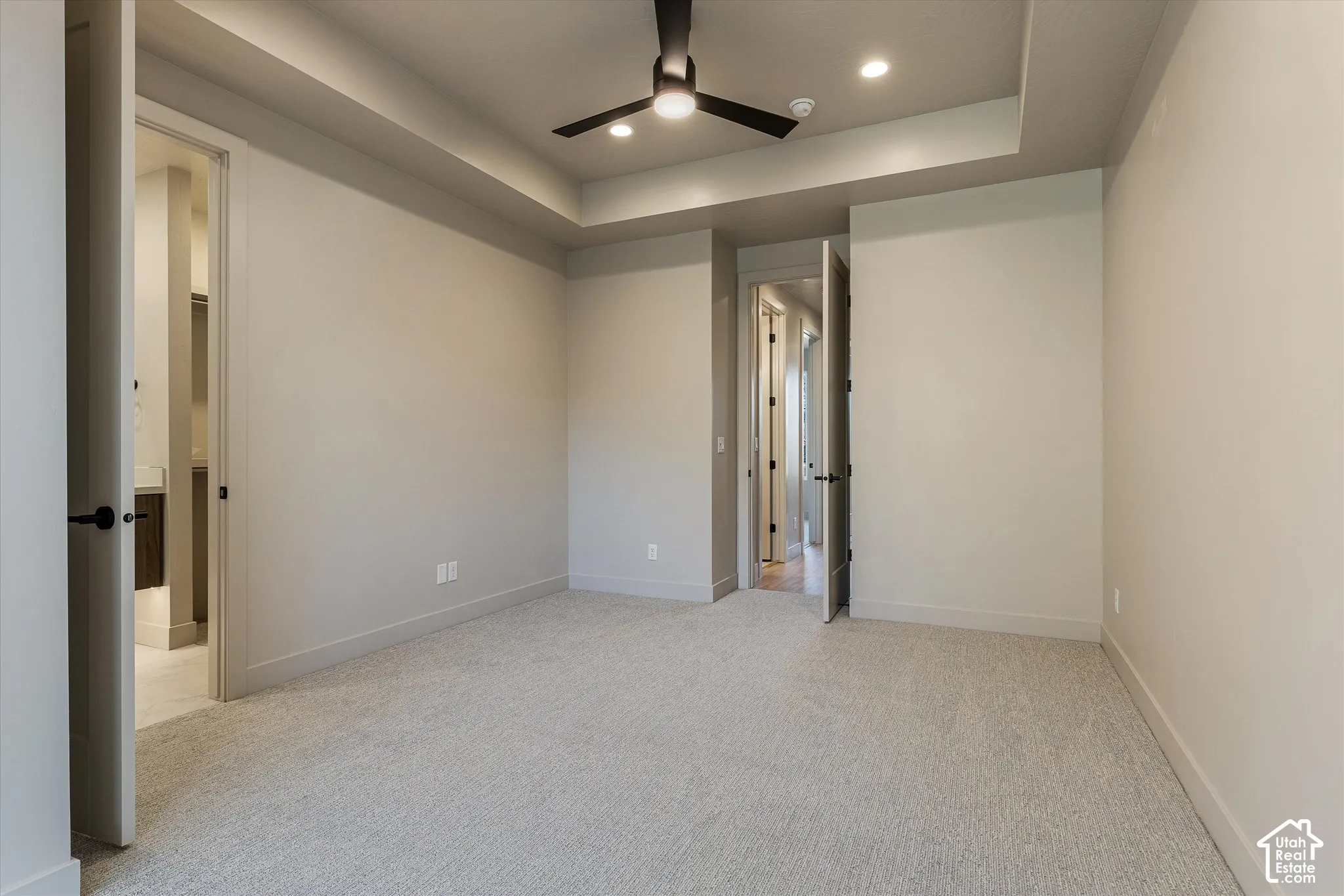 Recessed ceiling with integrated lighting, a ceiling fan, and light-toned carpeting