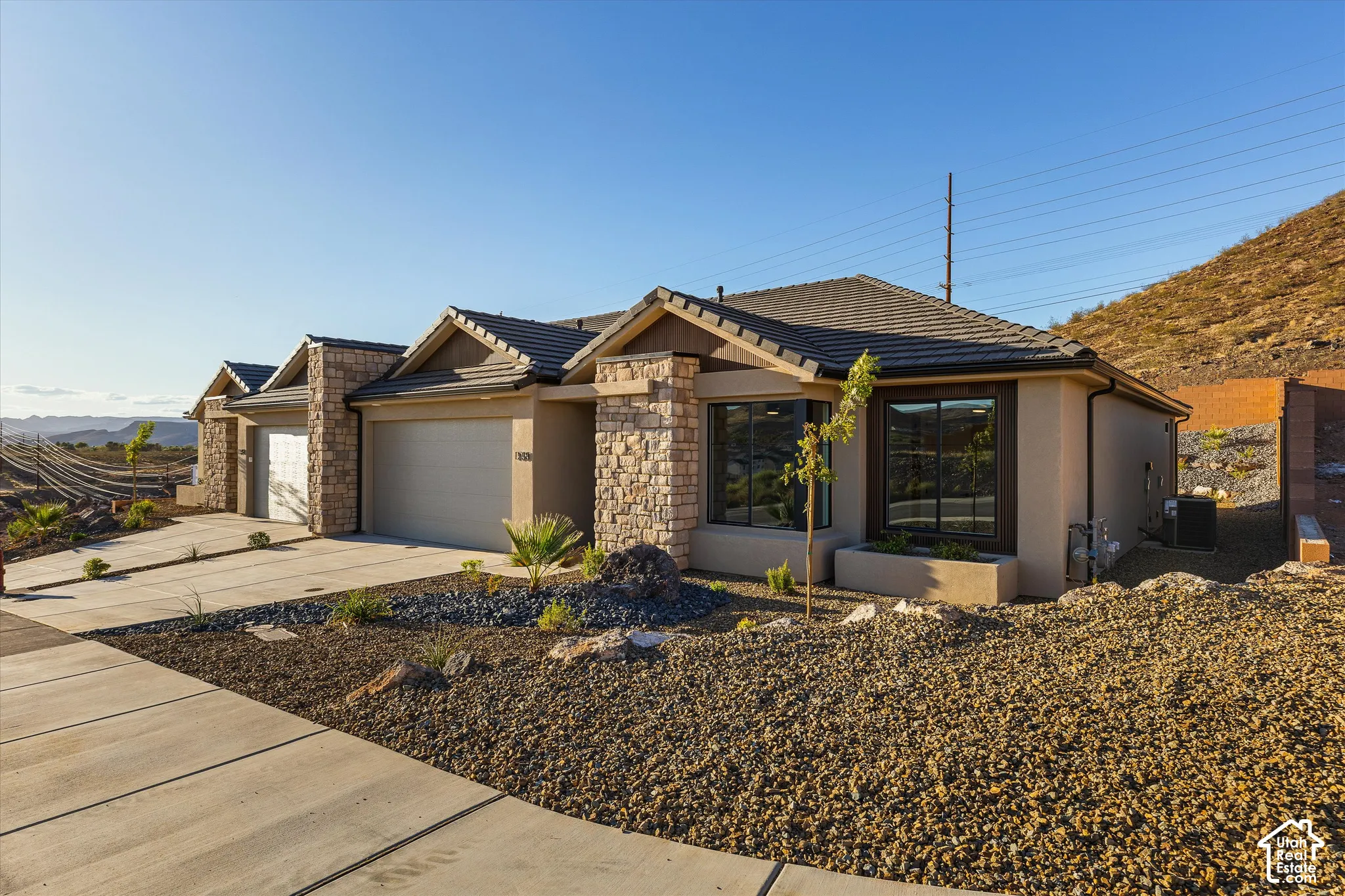 Stone veneer facade, stucco exterior, multi-pane windows, attached garage, and tile roof