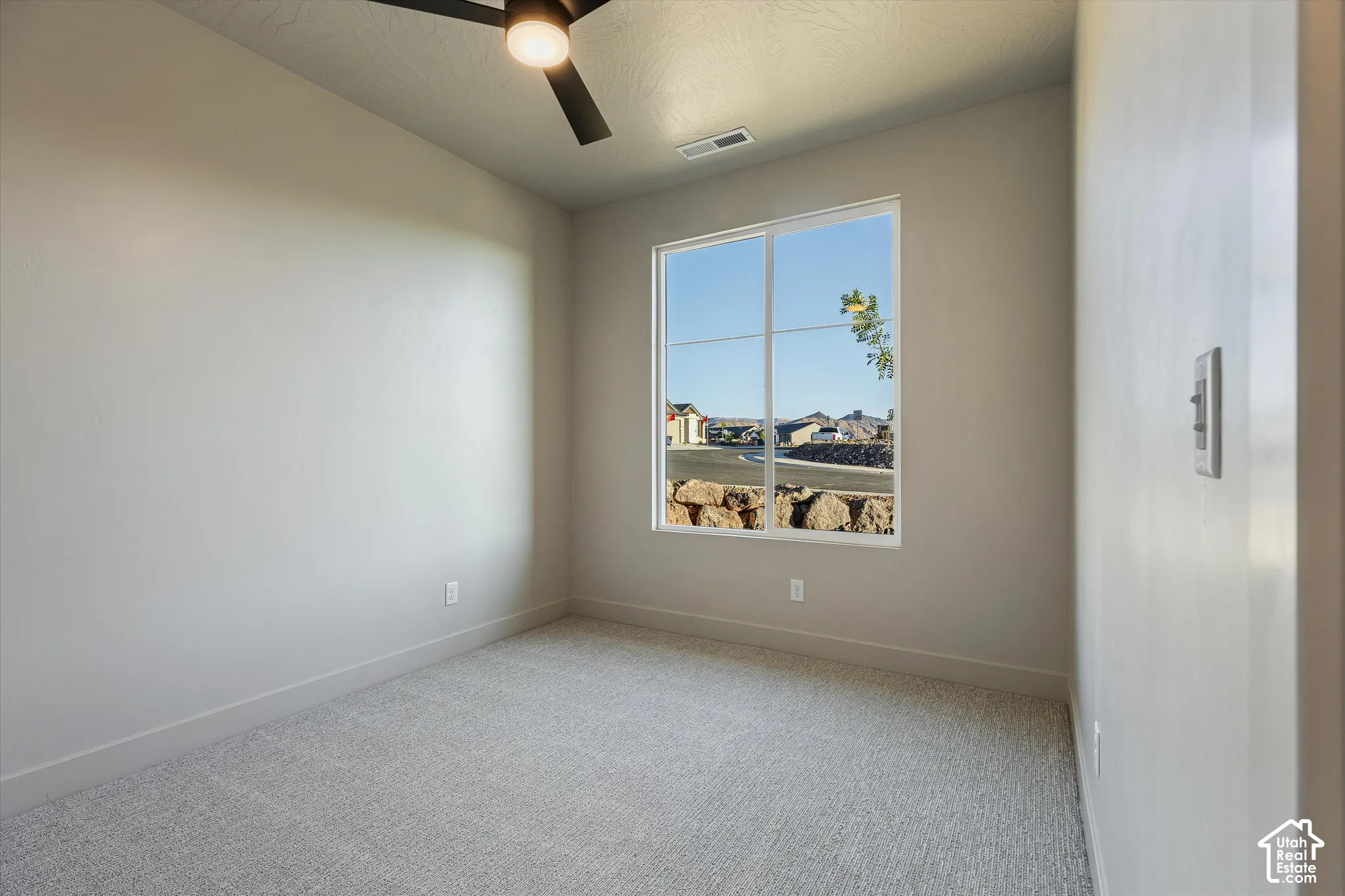Carpeted room featuring a ceiling fan, a window, and light-colored walls
