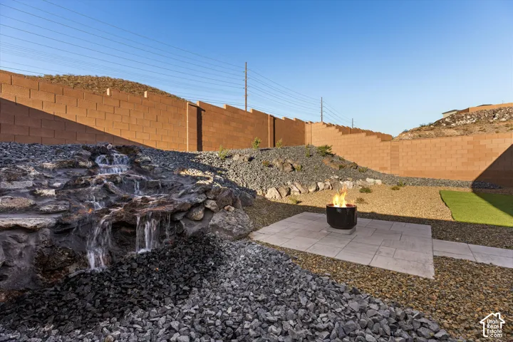 Stone water feature, paver patio, fire pit, artificial turf, and a block wall perimeter