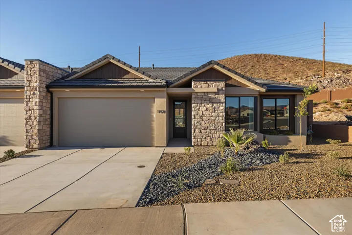 Stone veneer facade and columns, attached garage, large front windows, and a low-maintenance landscape with decorative rock