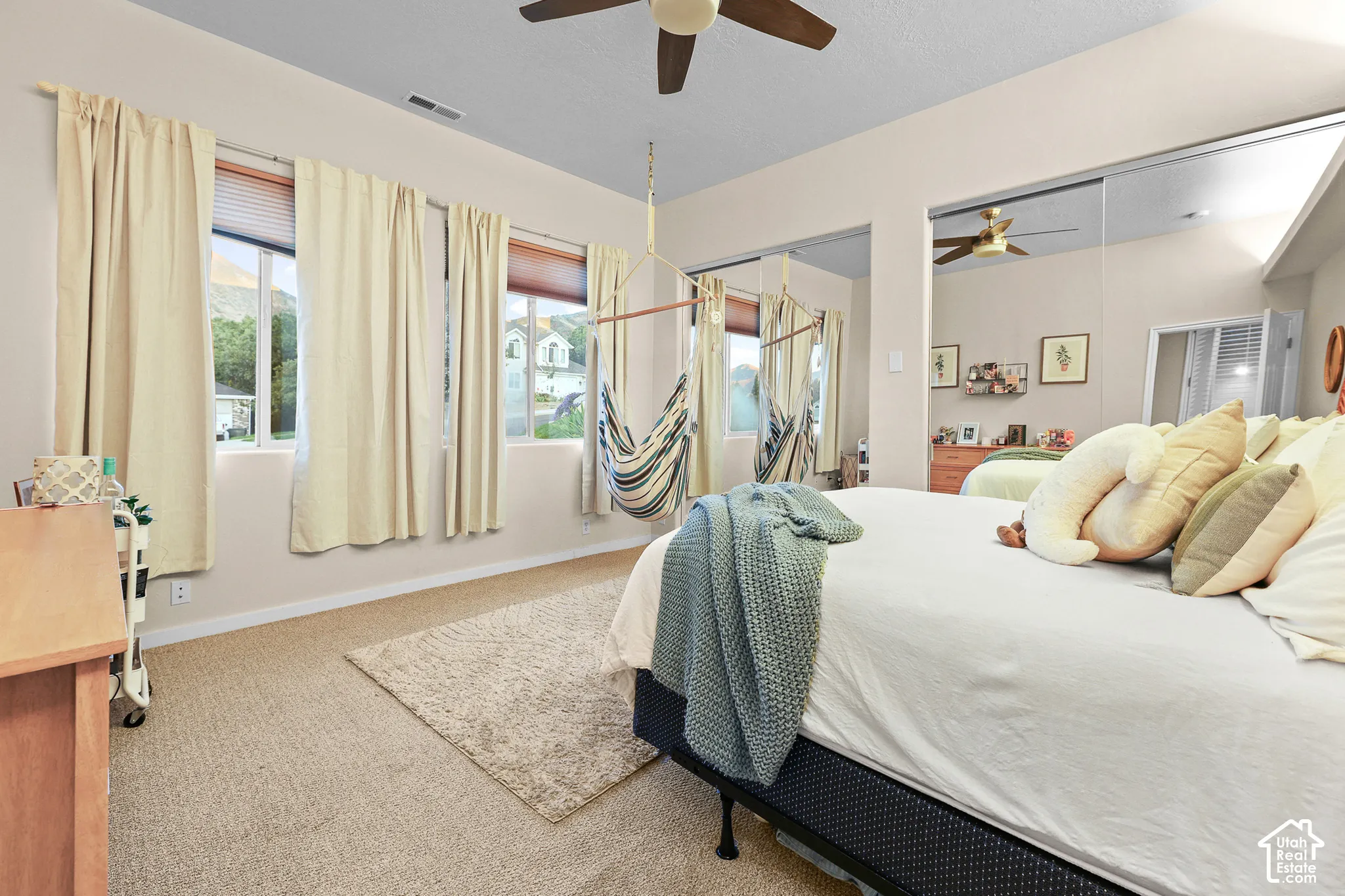 Recessed windows with blinds, mirrored sliding closet doors, ceiling fan, and carpeted flooring