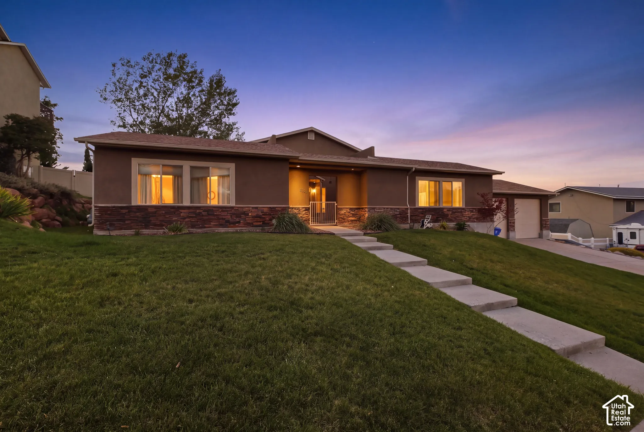 Stucco exterior with stone veneer accents, multi-pane windows, covered entry, and attached garage