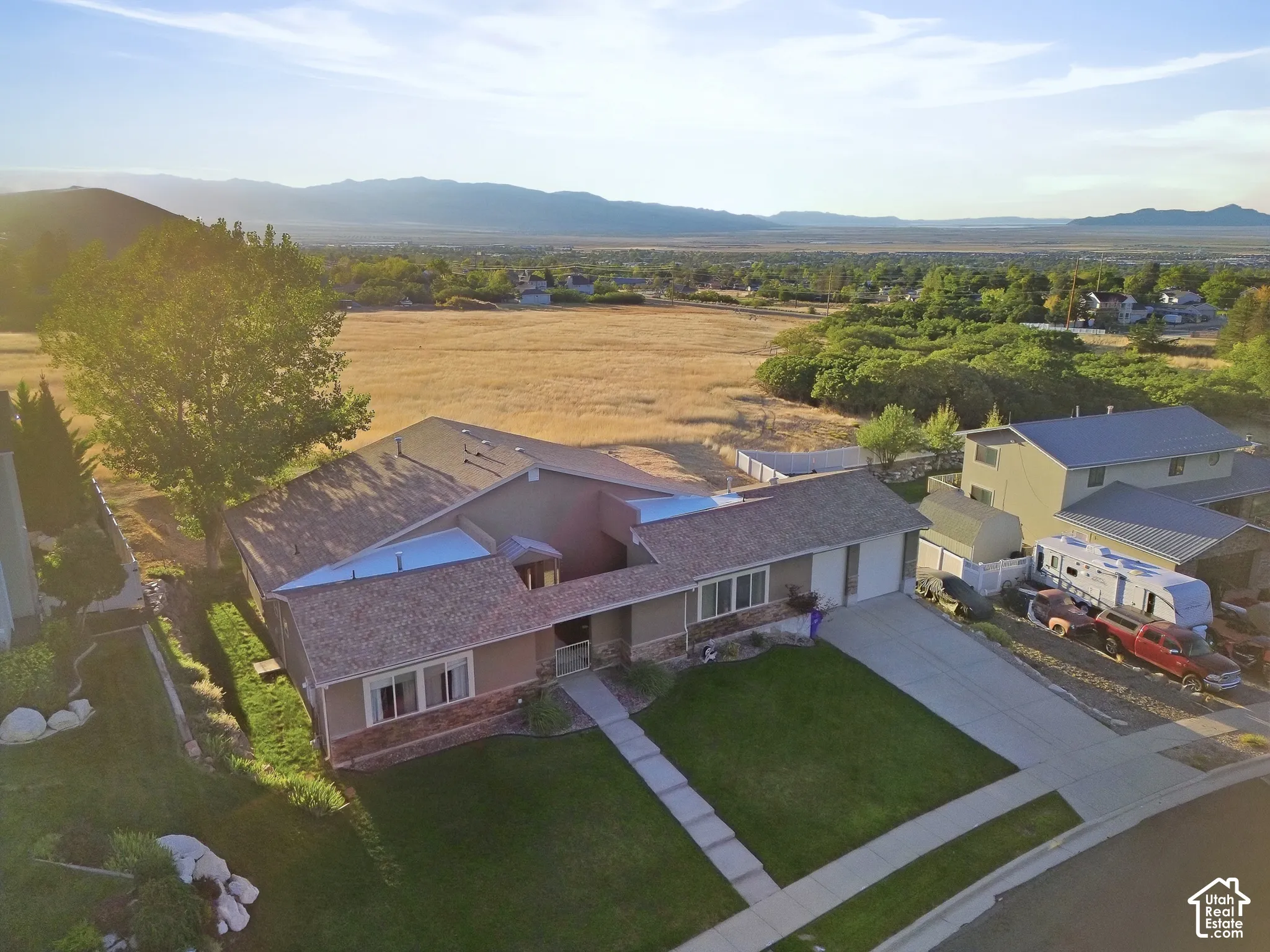 Front exterior featuring a multi-tone facade with stone and stucco finishes, an attached garage, a concrete driveway, and a landscaped front yard with a manicured lawn
