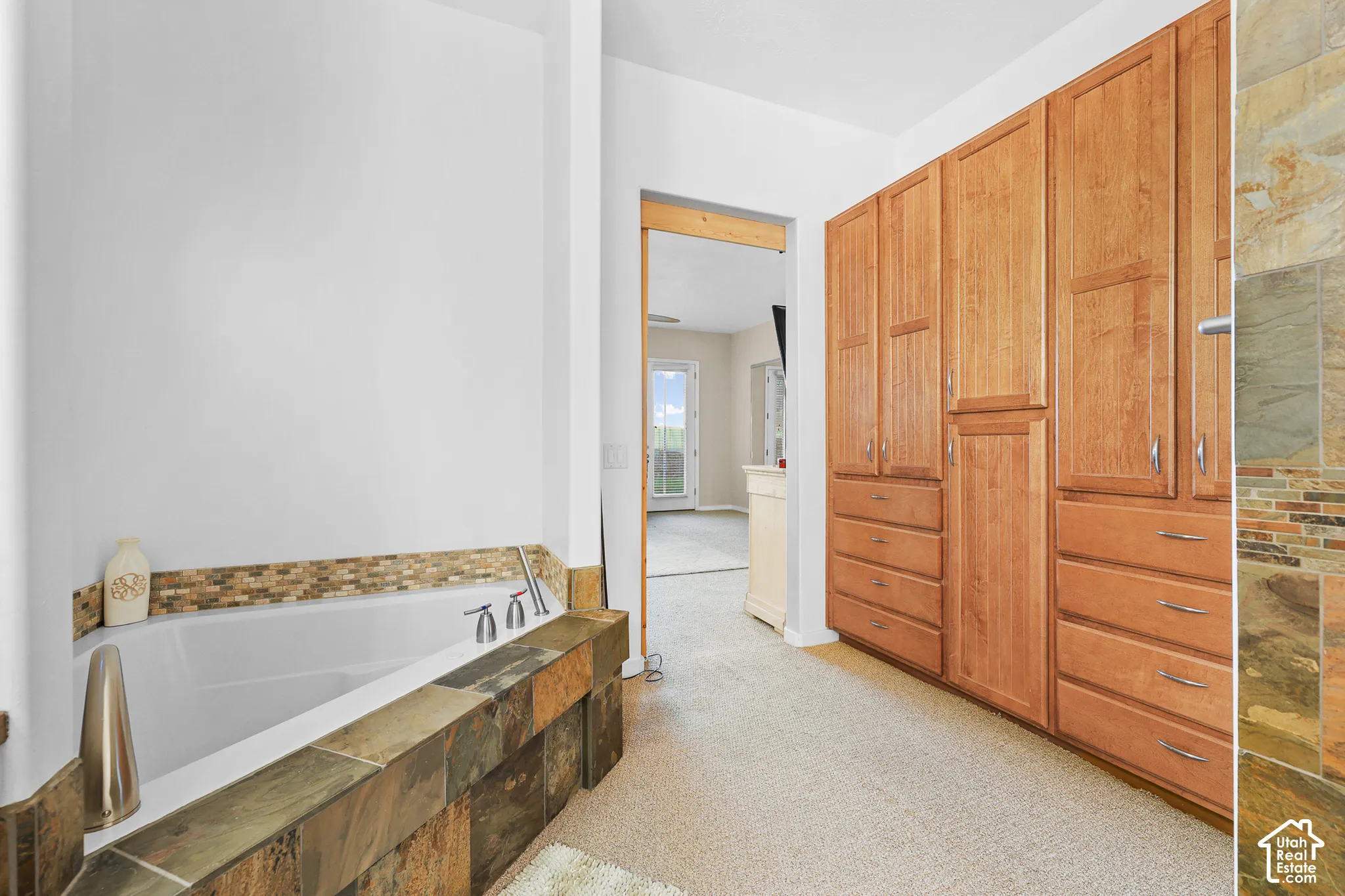 Soaking tub with mosaic tile surround and deck-mounted fixtures