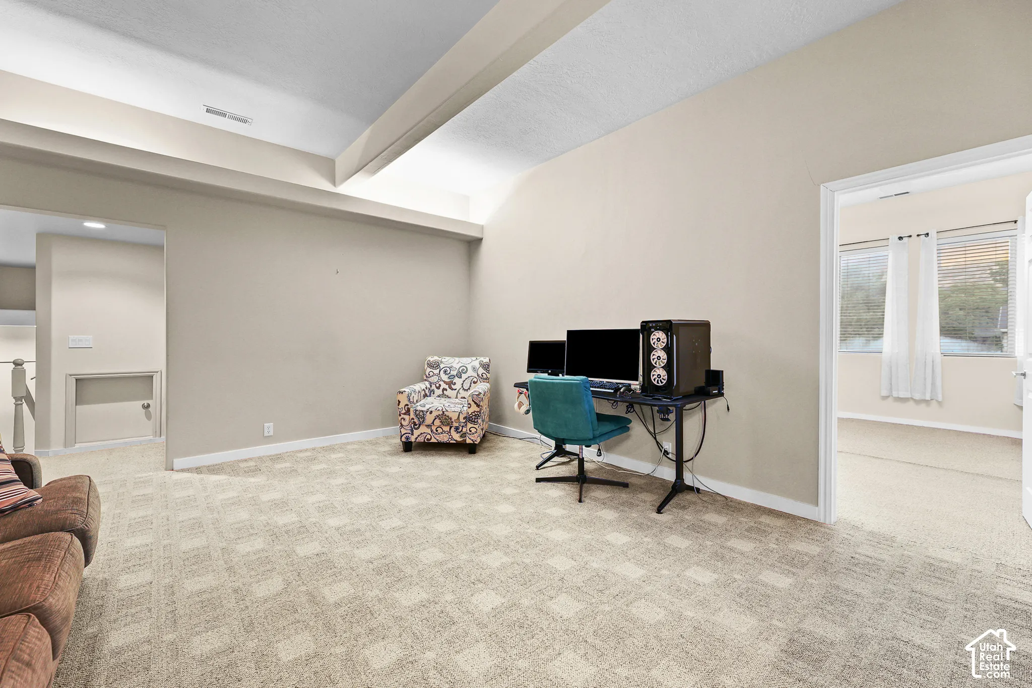 Carpeted room with a vaulted ceiling and neutral wall tones