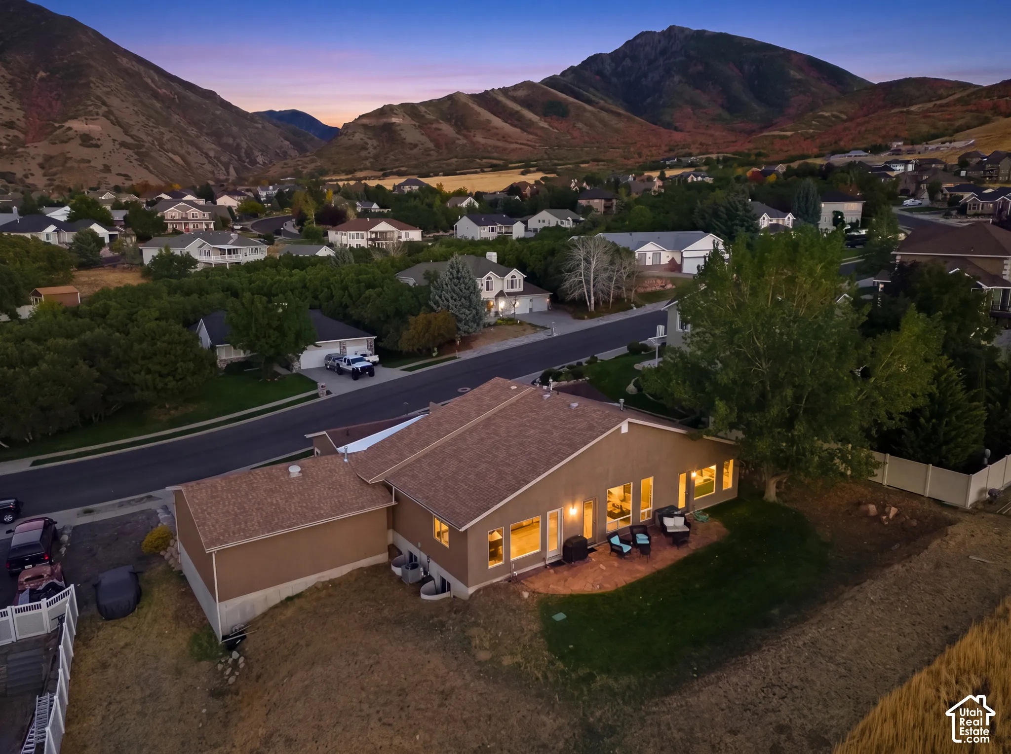 Expansive mountain backdrop, single-story property, large rear windows, outdoor patio with hardscaping, and a generous lawn area