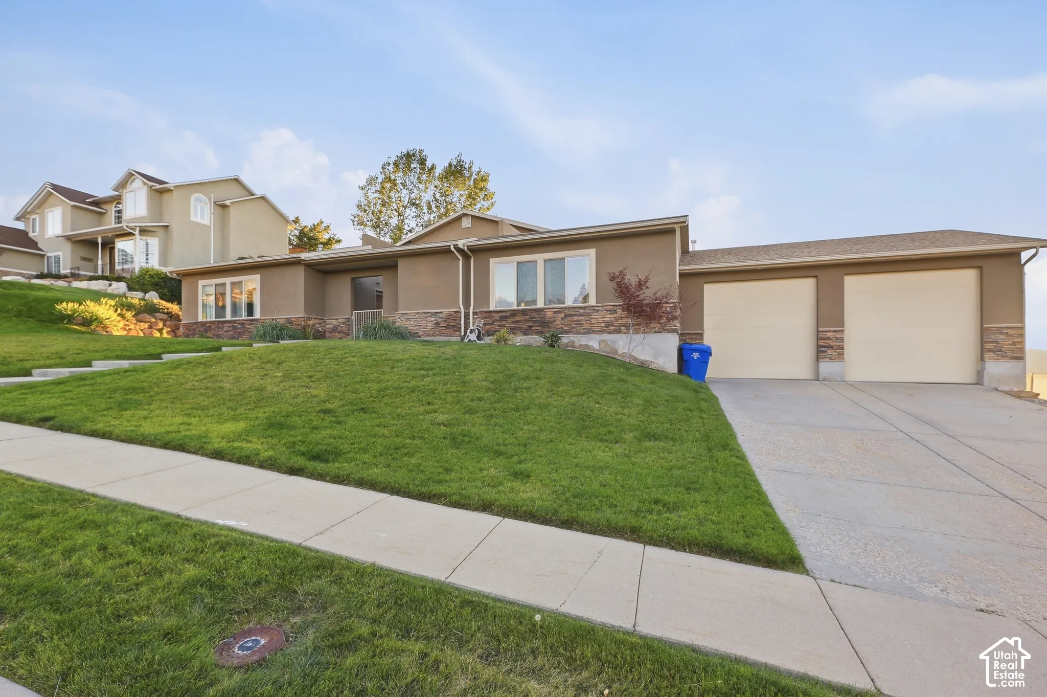 Stucco exterior with stone accents, mature landscaping, and a multi-car garage