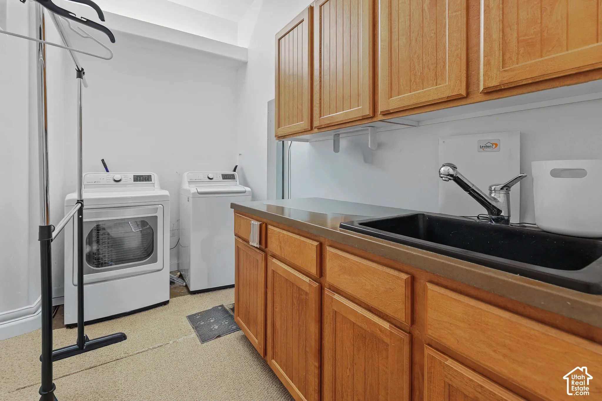 Laundry area with wood-finish cabinetry, built-in sink, and countertop