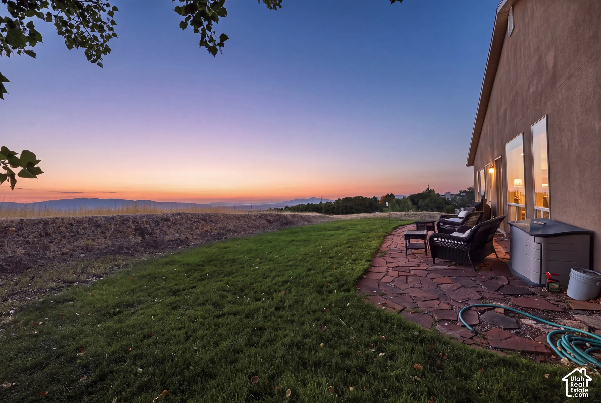 Stucco exterior with multiple windows, featuring an expansive lawn and a flagstone patio