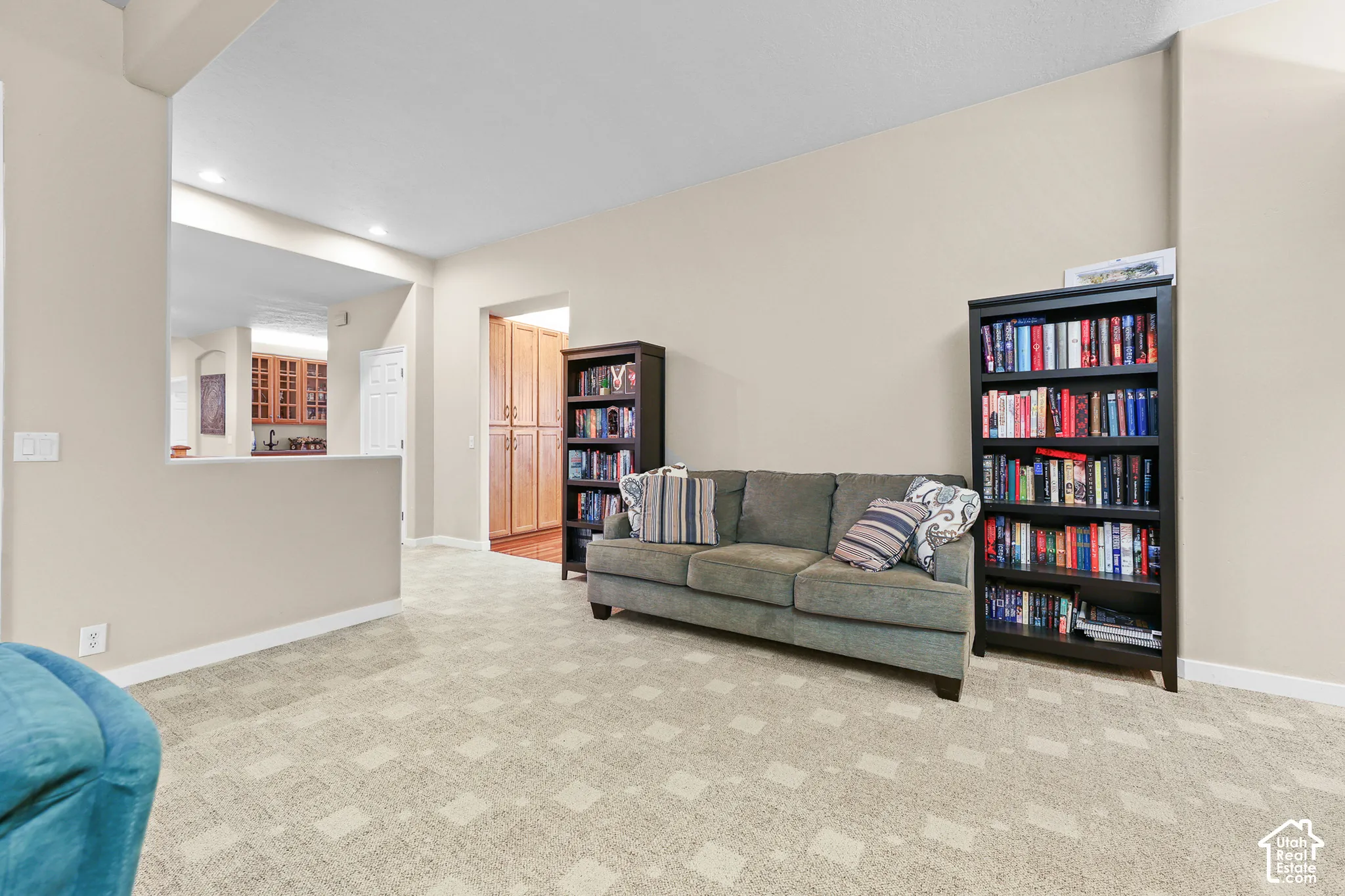 Open-concept living area with patterned carpeting, neutral wall tones, and recessed lighting
