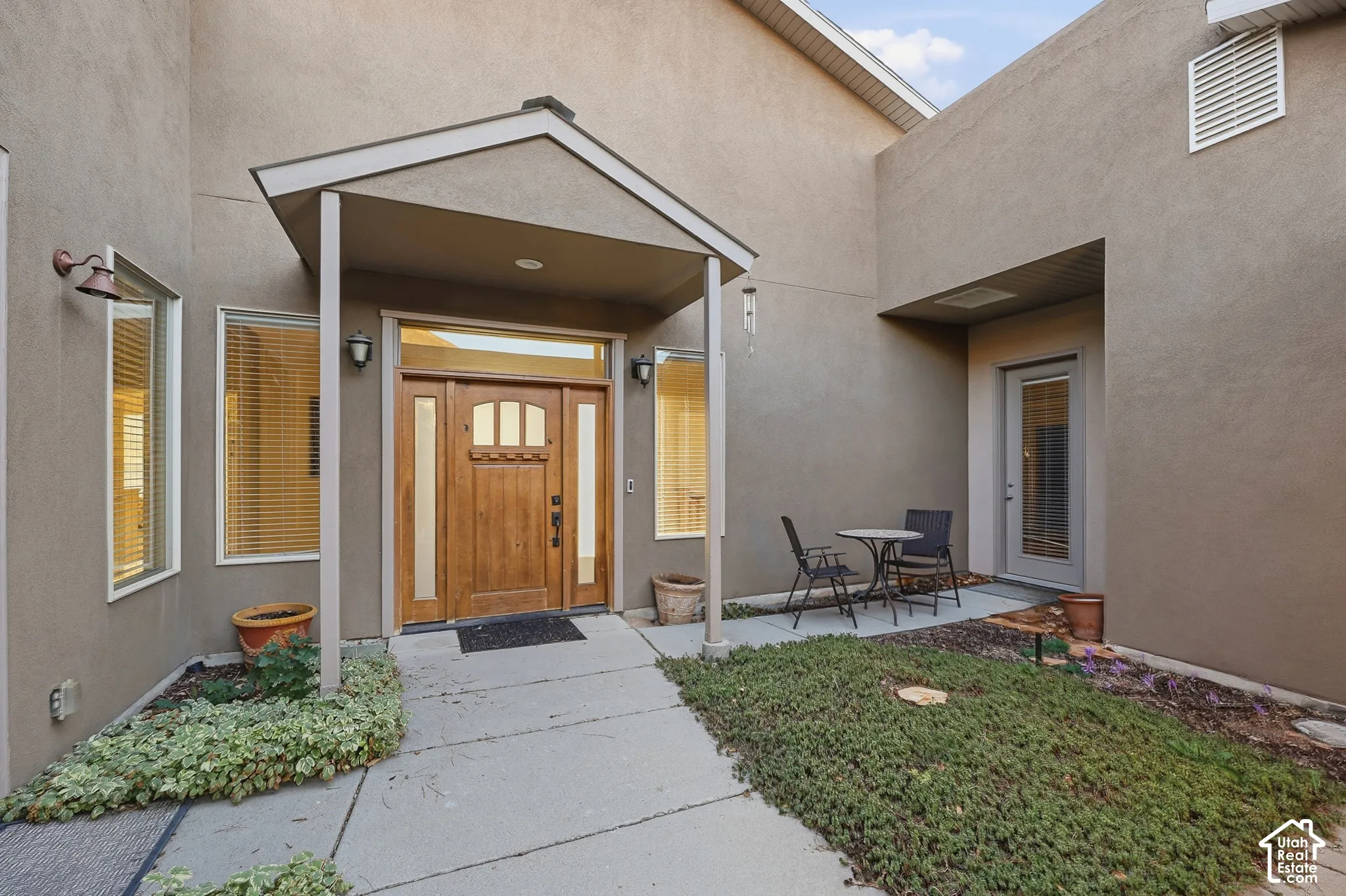 Stucco exterior with a covered entry, wood-paneled front door, and transom window