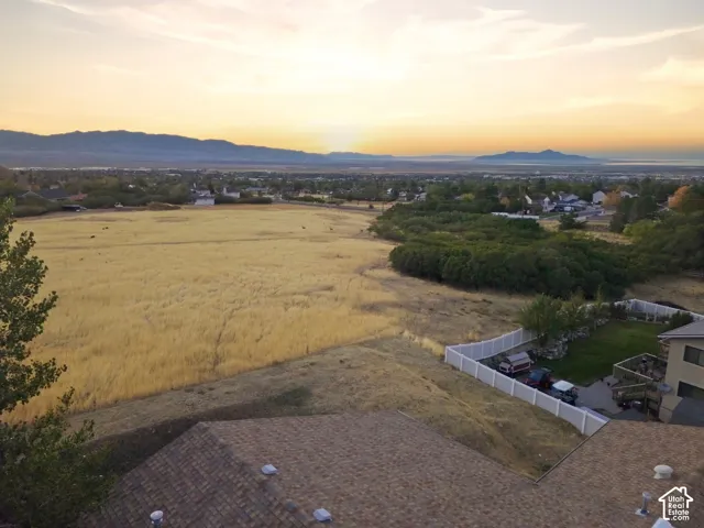 Expansive golden fields with distant mountains and a serene sky