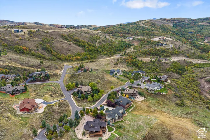 Winding roads through a residential area with varied home designs, set against a backdrop of rolling, tree-covered hills