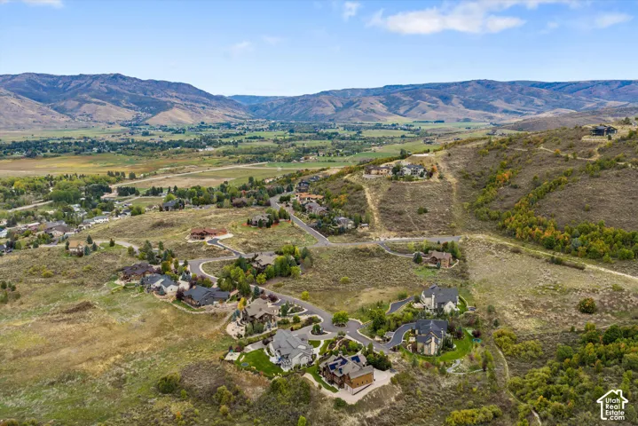 Aerial perspective showcasing mountainous terrain, surrounding natural landscape, and residential properties