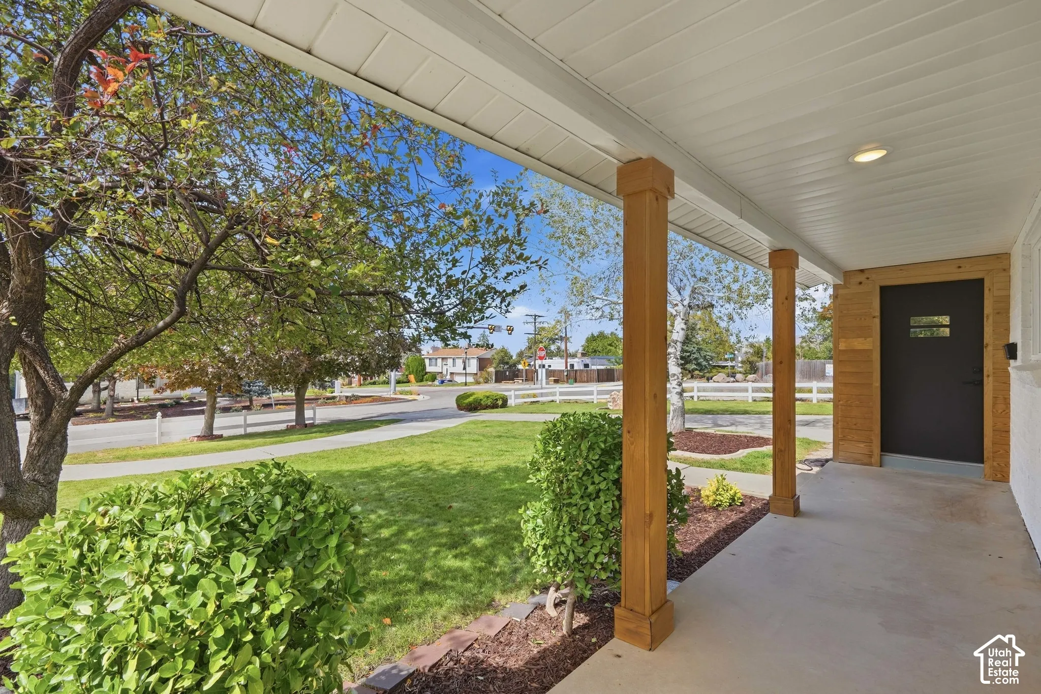 Covered front porch with wood-finish columns, concrete flooring, and a recessed ceiling light