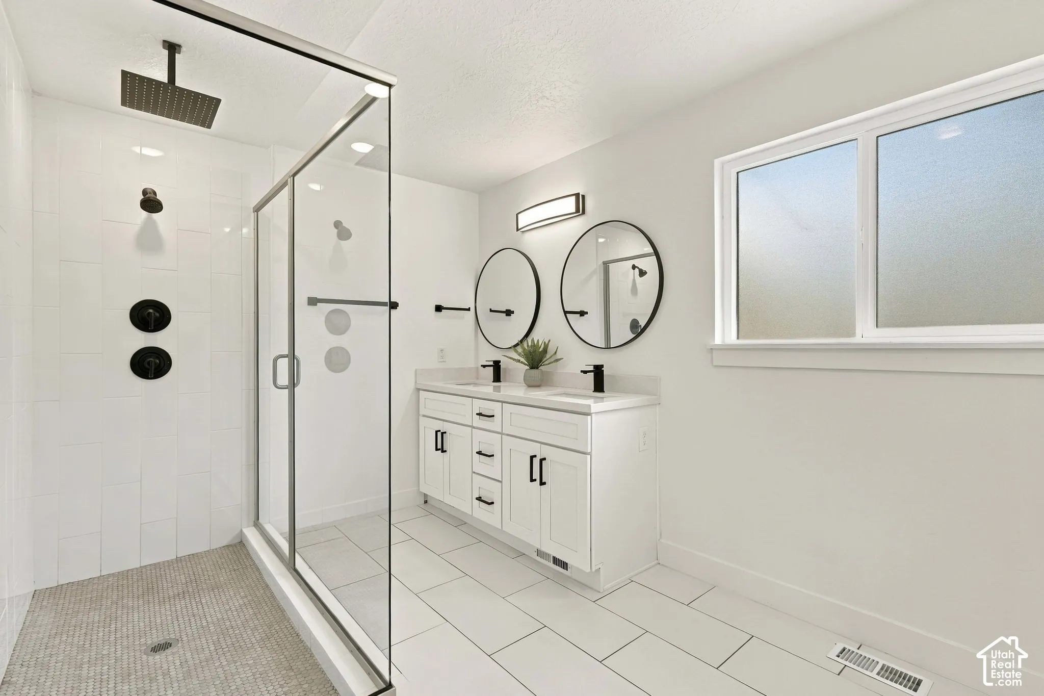 Walk-in shower with clear glass enclosure and matte black fixtures