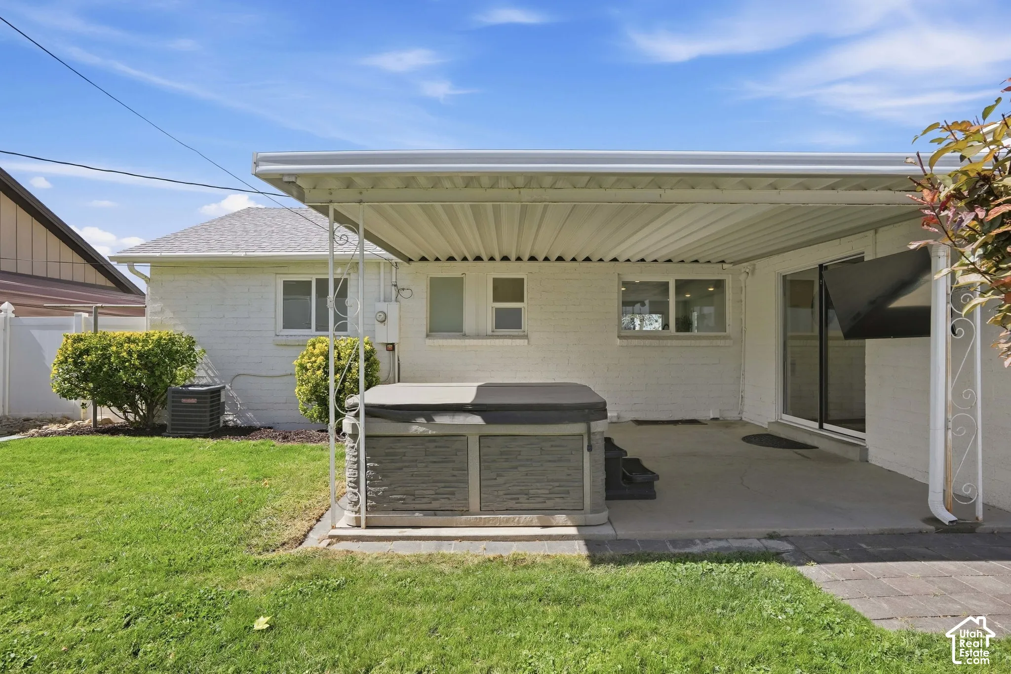 Backyard featuring a covered patio, concrete surface, and a hot tub