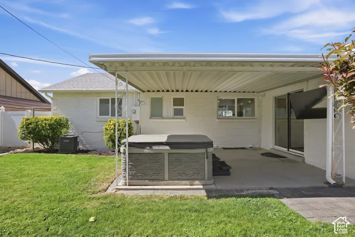 Backyard featuring a covered patio, concrete surface, and a hot tub