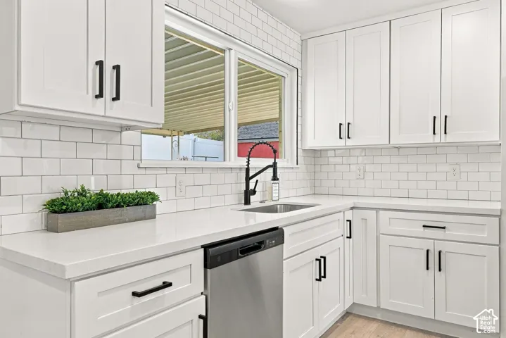 White shaker cabinetry with matte black hardware, white subway tile backsplash, and a black gooseneck faucet sets the stage for fun family gatherings and BBQs.