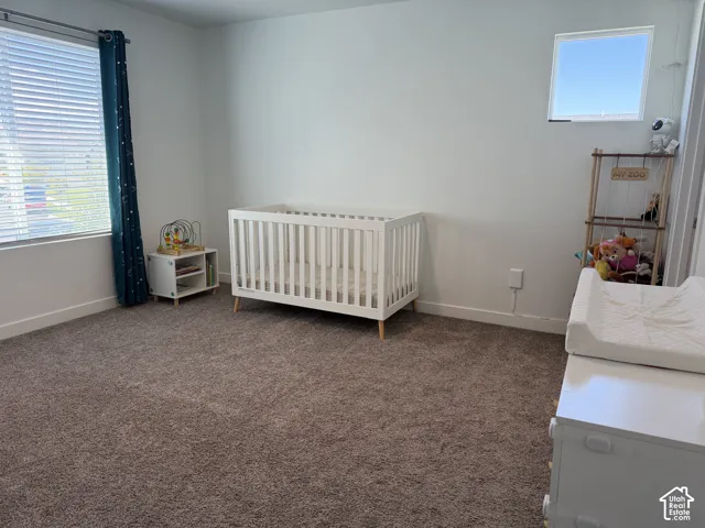 Spacious interior with neutral wall tones, large window with blinds, and durable carpeting