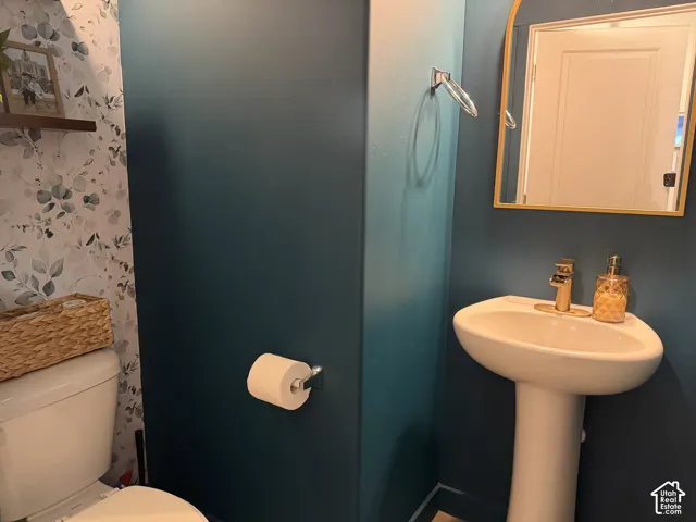 Pedestal sink with gold-tone faucet, framed mirror, and decorative accent wall