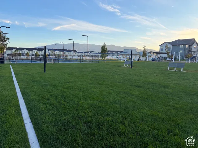 Expansive green space featuring a marked field, tennis courts, and park benches