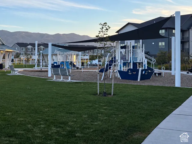 Community playground featuring a large play structure, built-in shade sail, and surrounding green space
