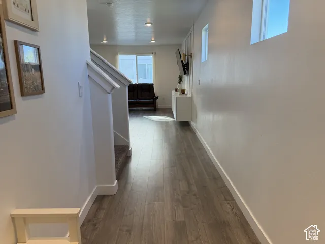 Wood-finish flooring, white walls, recessed ceiling lighting, and a white staircase with carpeted treads