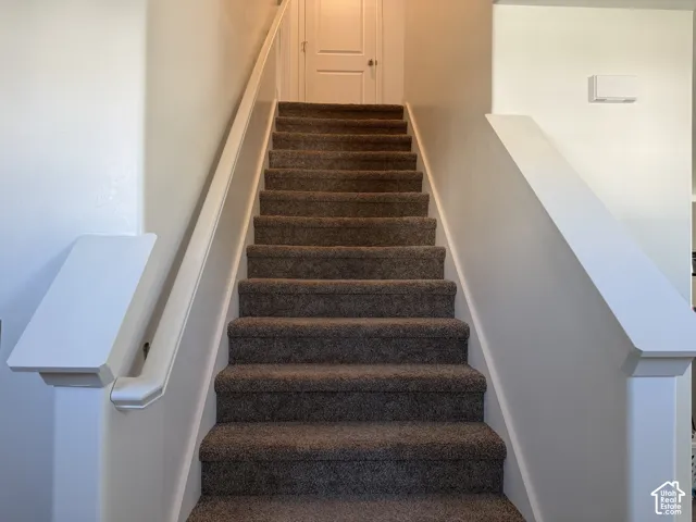 Carpeted staircase with white painted handrails
