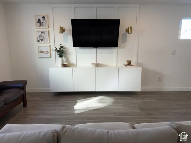 Wall-mounted media console with integrated storage, accent paneling, and wood-finish flooring