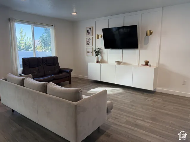 Recessed lighting, wood-finish flooring, white walls, built-in media console, and a large window