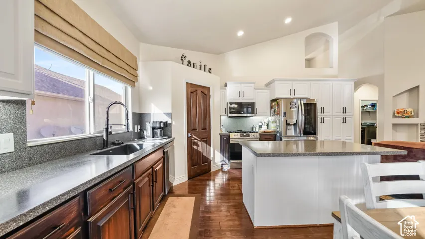 Kitchen featuring wood  flooring, white upper cabinetry, custom milled lower cabinetry, a center island with countertop seating, and recessed lighting
