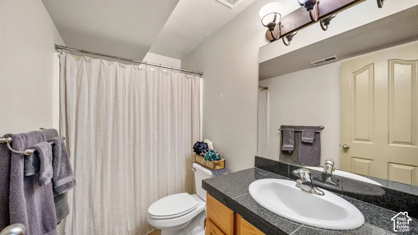 Bathroom with a vanity featuring a dark stone countertop, white oval sink, and a chrome faucet