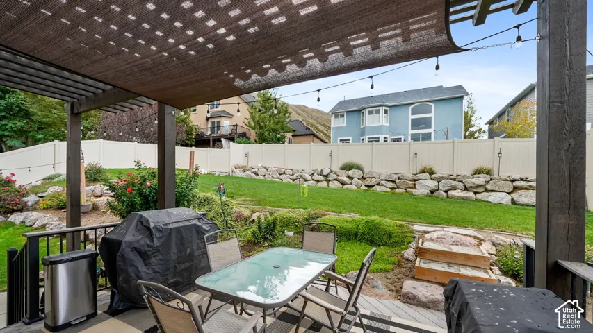 Expansive backyard featuring a shaded patio, built-in rock landscaping, and a manicured lawn