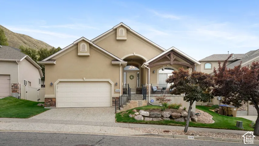 Stucco exterior with stone accents, a covered front porch, and an integrated two-car garage