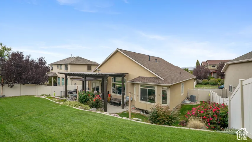 Expansive backyard featuring a manicured lawn, a paved patio, and a wood pergola structure