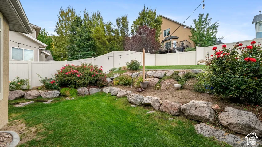 Manicured lawn with a landscaped rock garden, mature shrubs, and a privacy fence