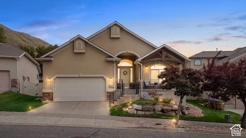 Stucco exterior with stone accents, covered front porch, integrated garage, and landscaped front yard with established plantings.  Year Round Jelly Fish lighting. Twilight Effect