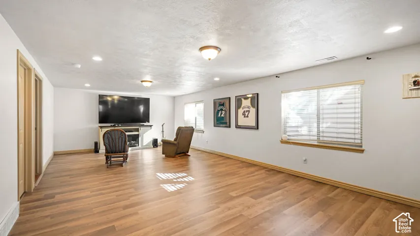 Spacious theater room featuring wood-finish flooring, recessed lighting, and dual windows with horizontal blinds