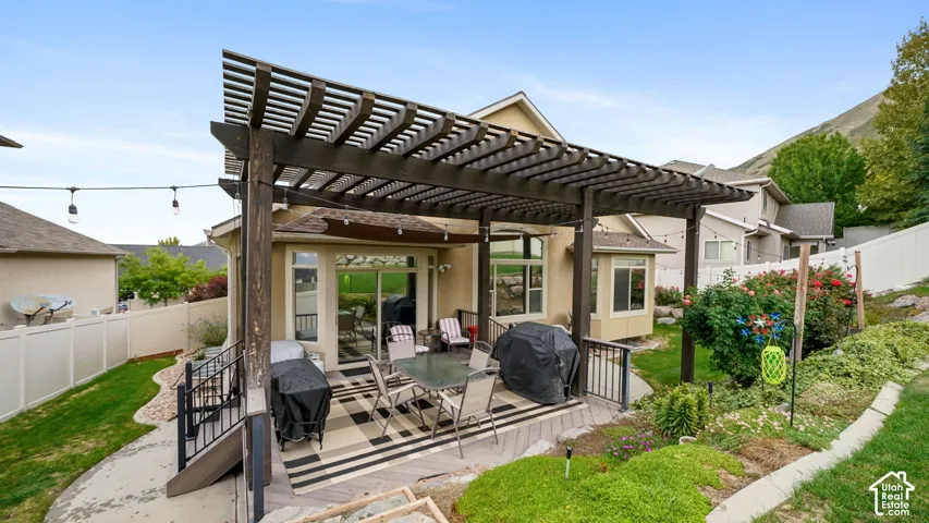 Expansive outdoor patio with a wooden pergola, leading to a landscaped yard and a privacy fence