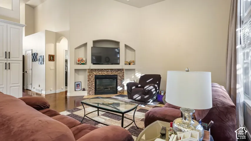 Vaulted ceilings, wood-finish flooring, stone-faced fireplace, built-in shelving, and arched doorways