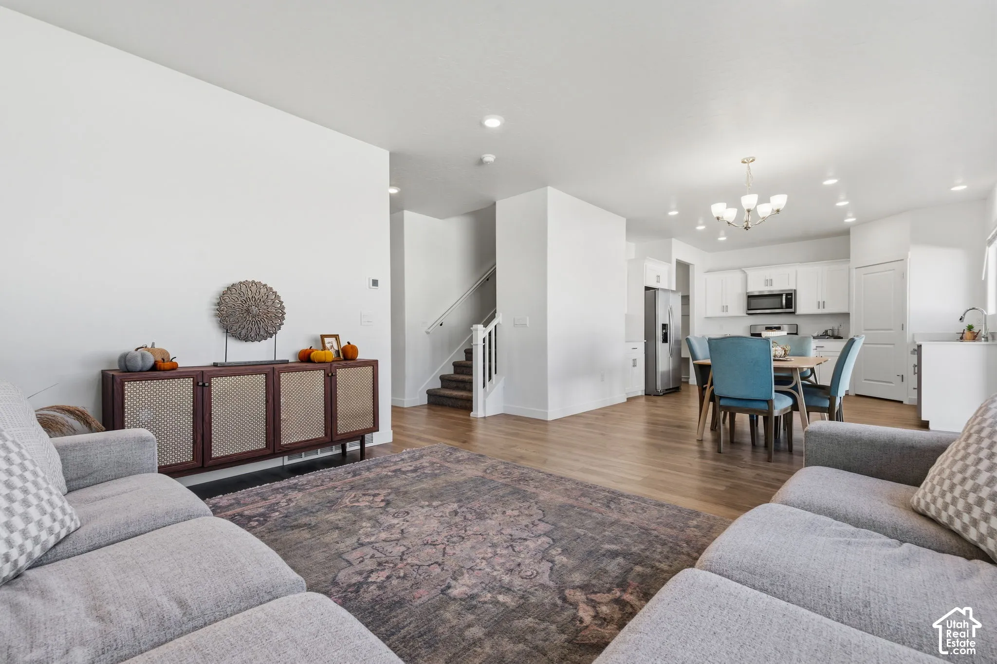 Open-concept living space featuring wood-finish laminate flooring, recessed lighting, white cabinetry, and stainless steel appliances