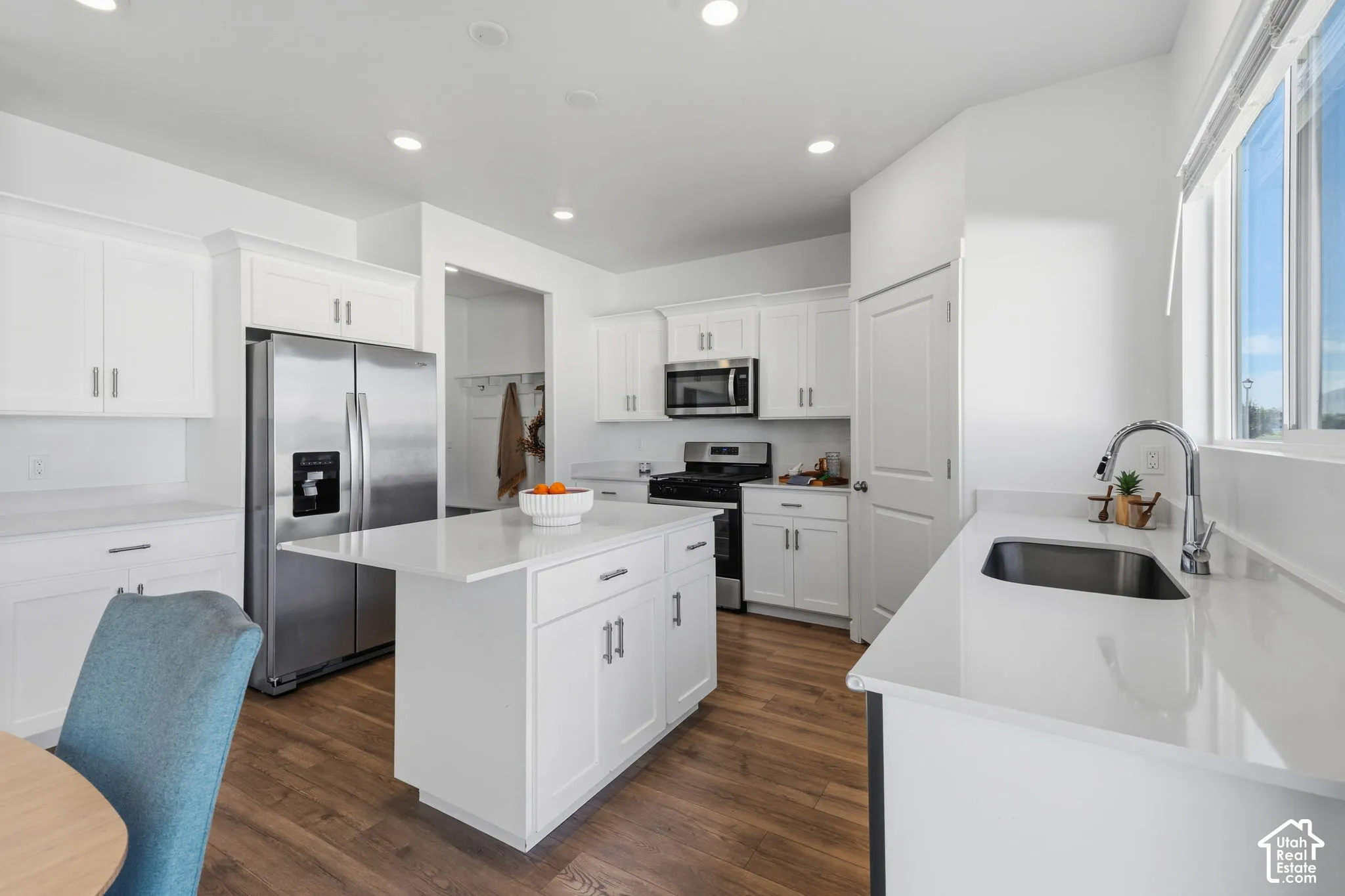 Bright kitchen featuring white cabinetry, stainless steel appliances, a center island and ample natural light