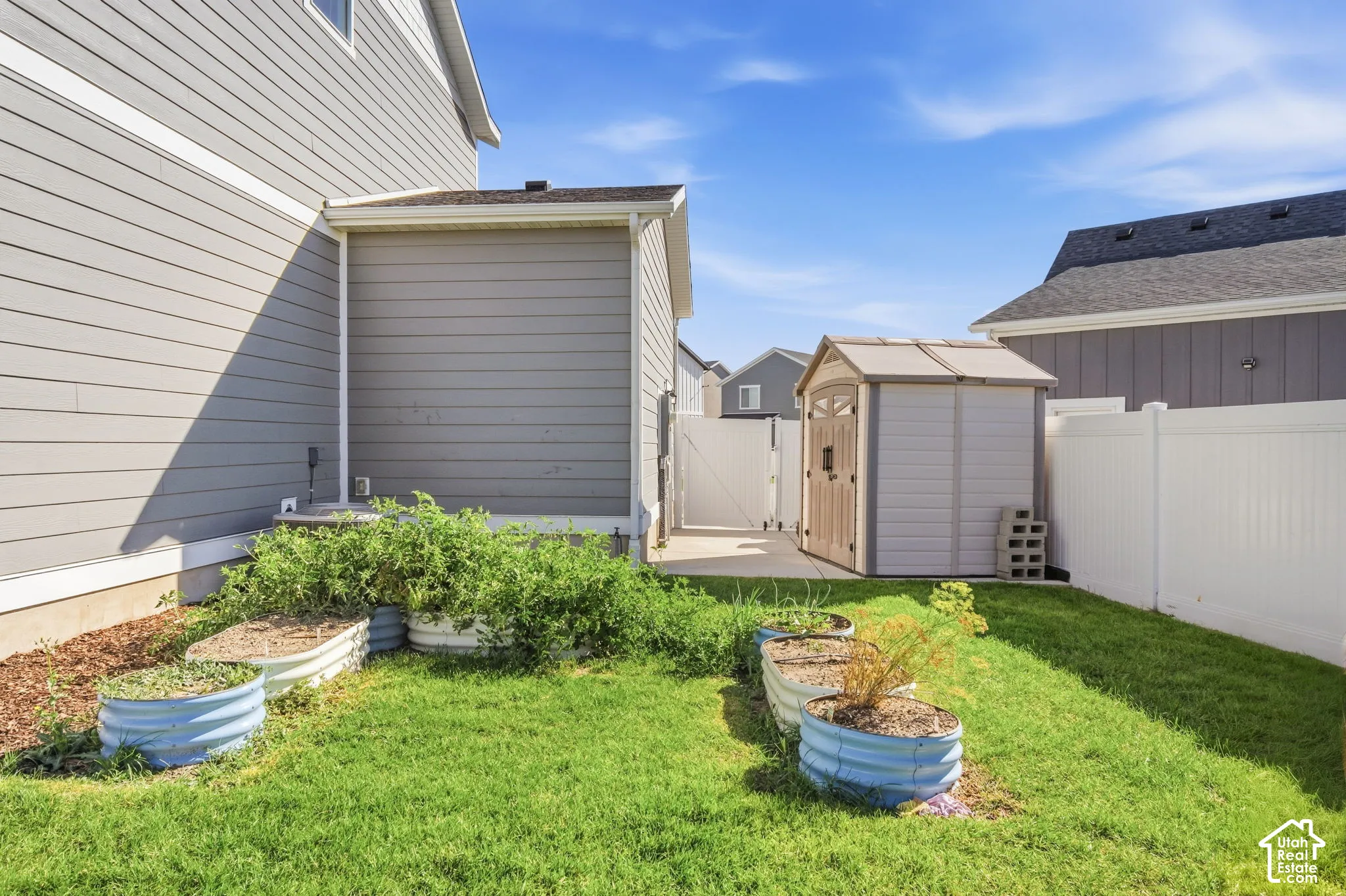Manicured lawn, raised garden beds, and a white privacy fence