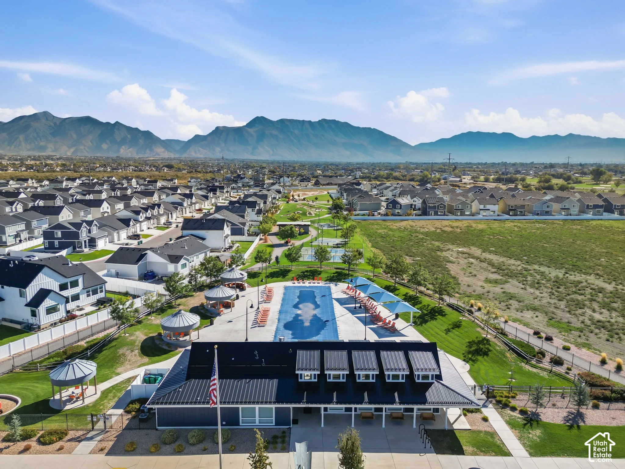 Community building with a large pool and surrounding lounge areas, additional outdoor seating, and mountain backdrop